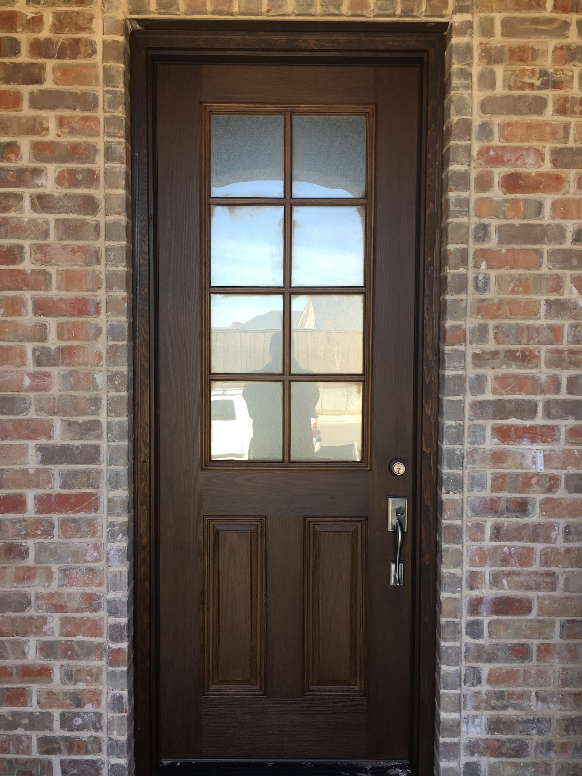 Stained front door set in red brick exterior