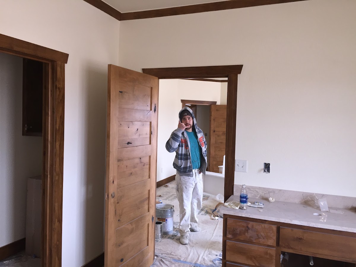 Painter at work in a freshly painted room with wood trim